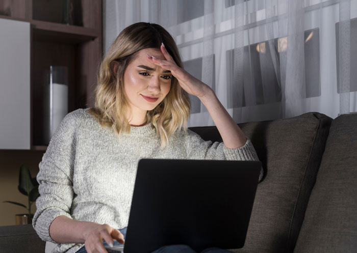 Young woman looking stressed while working on a laptop, depicting tension in a bride’s wedding power struggle scenario. Young woman looking stressed while working on a laptop, depicting tension in a bride’s wedding power struggle scenario.