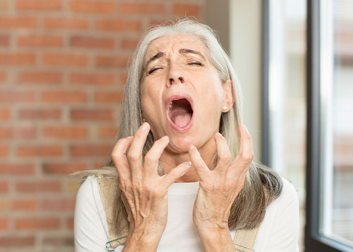 Middle-aged woman screaming indoors with frustration and anger, expressing intense emotions during a family gender reveal event.