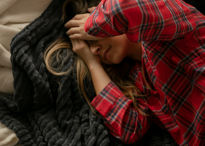 Woman covering her face in distress, lying on a bed with a red plaid shirt, depicting emotional conflict with stepfather. Woman covering her face in distress, lying on a bed with a red plaid shirt, depicting emotional conflict with stepfather.
