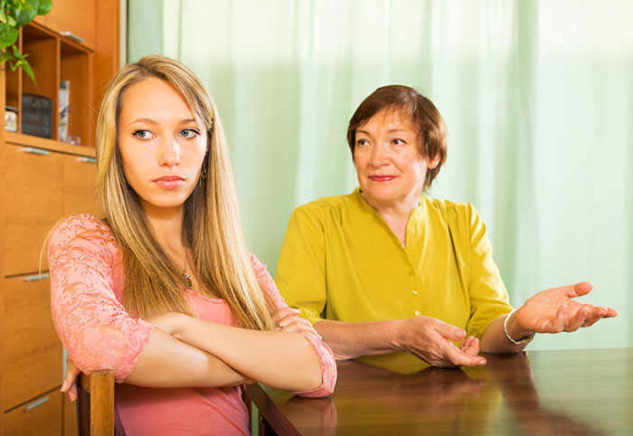 A young mom looking uncomfortable while her mother in law demands a more Christian baby name at the table.