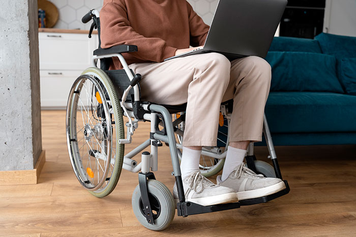Person in wheelchair using laptop, illustrating challenges faced when friends turn out to be total jerks.