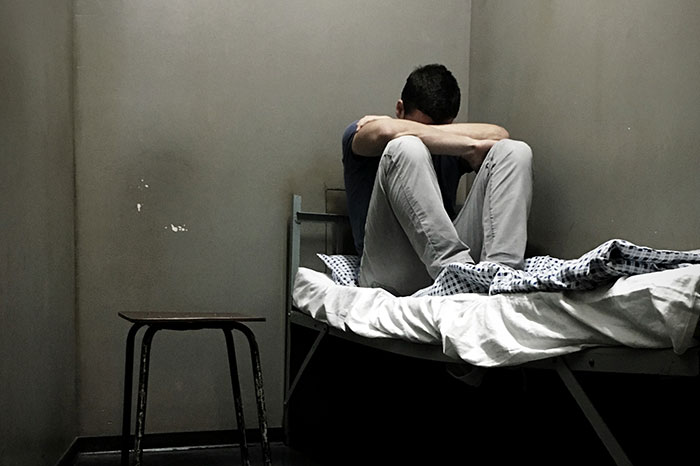 Man sitting alone on a bed in a dim room, showing fear and distress after a real-life encounter with psychopaths. - 18