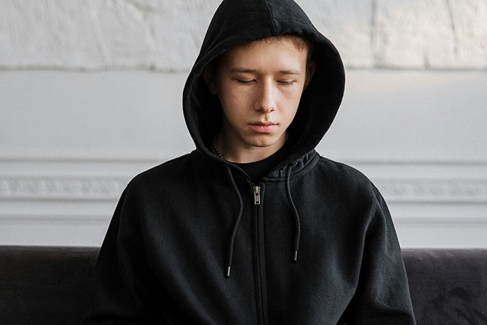 Teenager in a black hoodie looking down, reflecting the mood of real-life encounters with psychopaths that gave people goosebumps. - 9