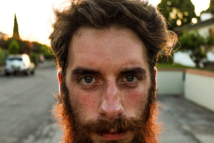 Close-up of a man with intense eyes and a red beard outdoors, evoking real-life encounters with psychopaths. - 13