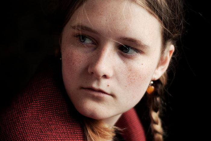 Young woman with braided hair wearing a red sweater looking sideways, evoking real-life psychopath encounters feeling - 3