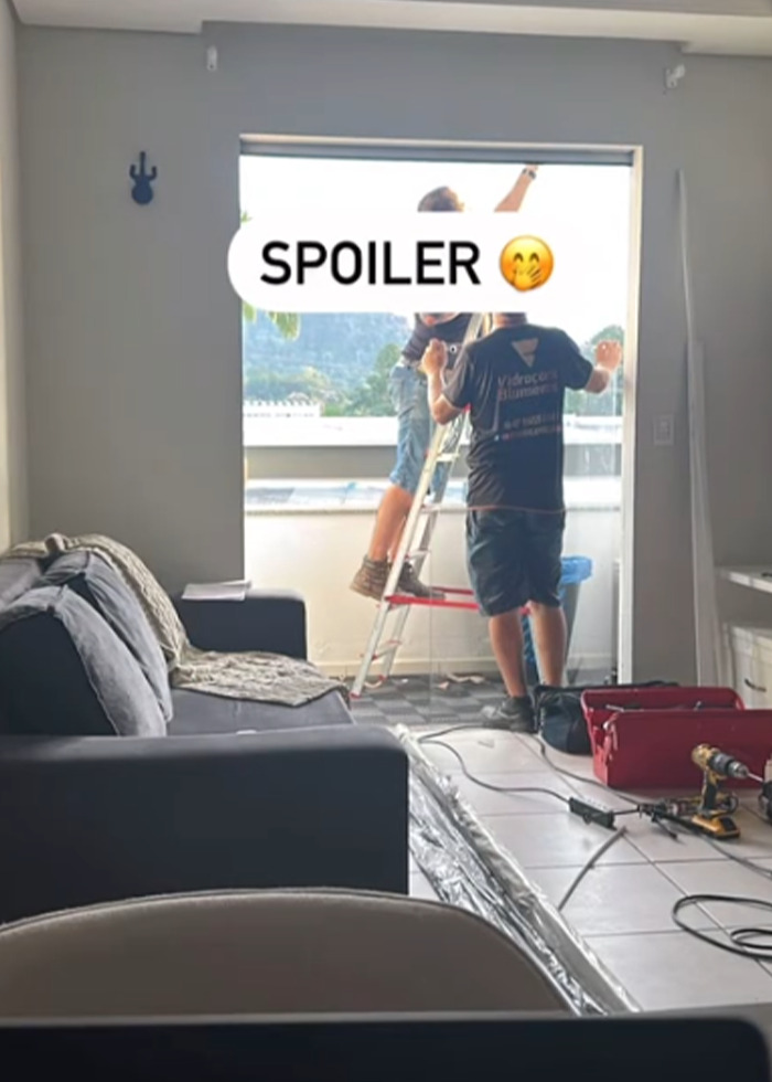 Two people working on balcony renovation in a living room, illustrating momfluencer using room as office with child on balcony.