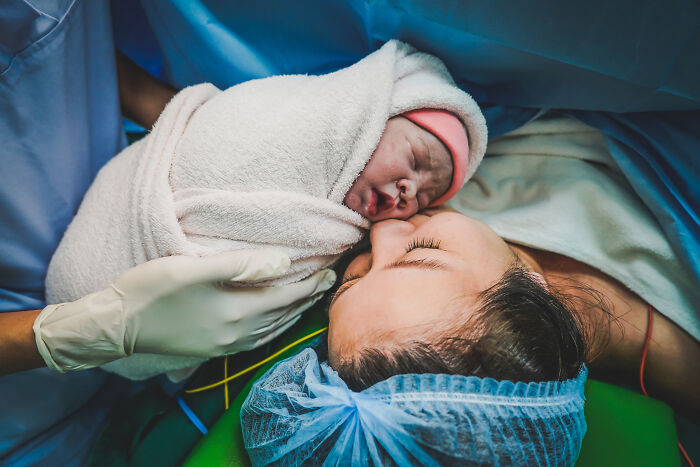 Newborn baby wrapped in a blanket held close to mother in a hospital setting representing toxic femininity behaviors. - 2