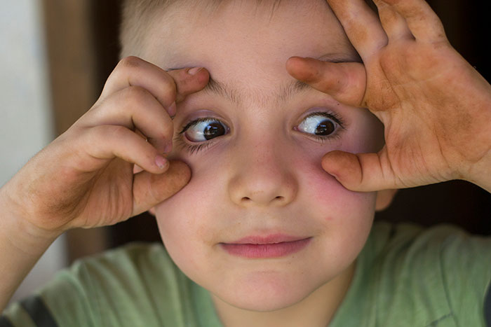 Young boy making a silly face with dirty hands, capturing a cringeworthy and classic school moment that left him red-faced.