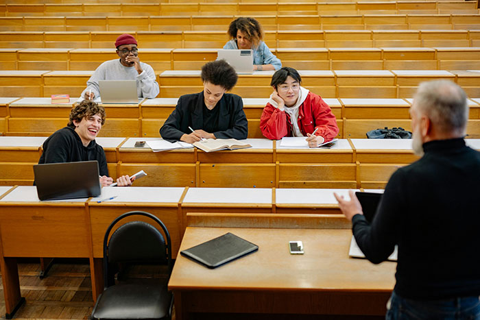 College students reacting during a lecture in a classroom, showcasing classic school moments with mixed emotions and engagement.