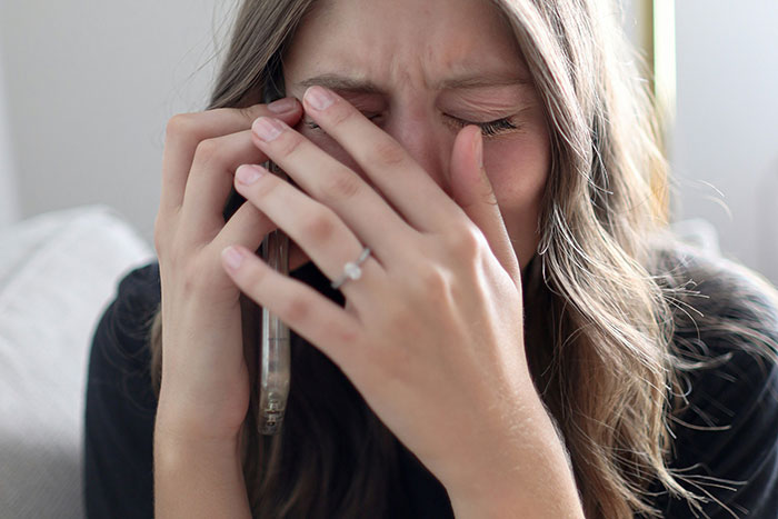 Young woman covering her face in embarrassment while talking on the phone, capturing cringeworthy school moments emotions.