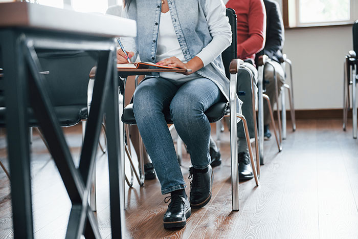 Student in a classroom writing in a notebook during a school moment that could be cringeworthy or classic.
