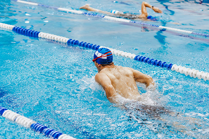 Teenage boy swimming in a pool during a school race representing classic school moments in sports activities.