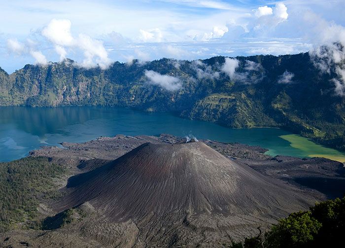 Aerial view of an active volcano surrounded by mountains and a lake, related to autopsy and drone footage findings.