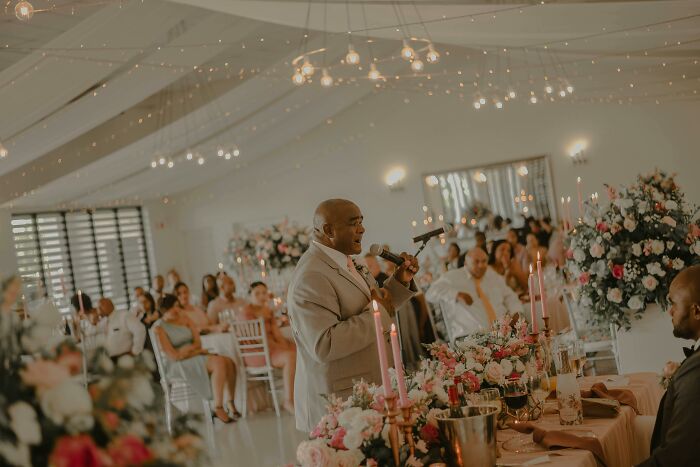 Man giving a speech at a decorated wedding with guests seated, highlighting stories of attending multiple weddings of the same person. - 19