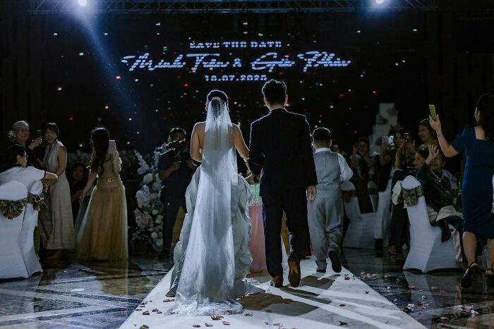 Bride and groom walking down the aisle during a wedding ceremony with guests capturing the moment on phones. - 28