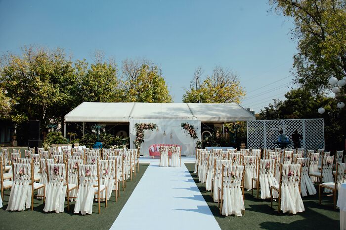 Outdoor wedding setup with white chairs and floral decorations, illustrating stories of attending multiple weddings. - 25