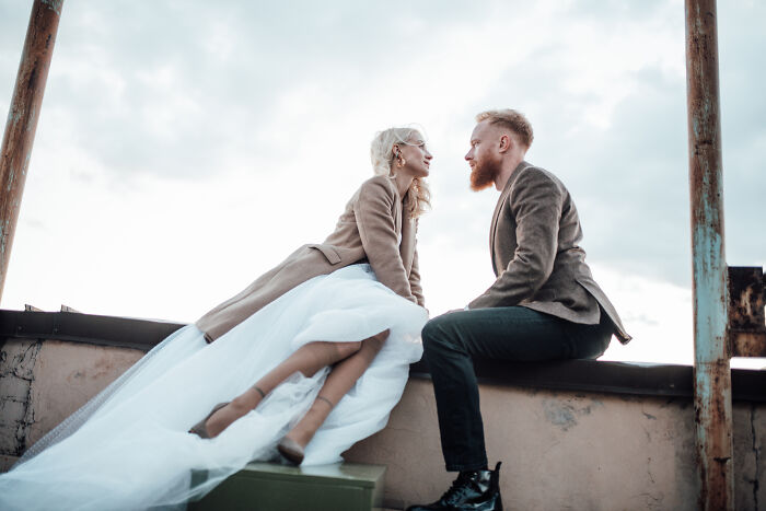 Couple facing each other on rooftop, bride in wedding dress and groom in jacket, symbolizing second and third weddings. - 14