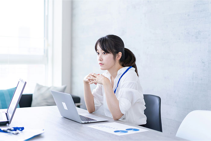 Korean woman working on laptop in office, appearing thoughtful about borderline racism and workplace name issues. Korean woman working on laptop in office, appearing thoughtful about borderline racism and workplace name issues.