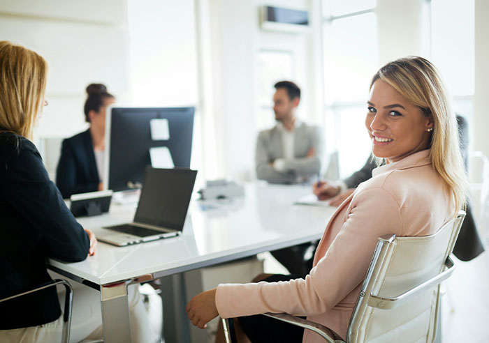 Woman in office smiling with coworkers, highlighting workplace interactions and potential Islamophobic behavior.