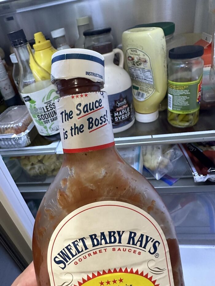 Bottle of Sweet Baby Ray's barbecue sauce inside a fridge with condiments, illustrating messy roommate fridge habits.