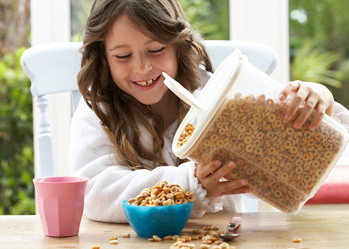 Young girl pouring cereal into a bowl, illustrating powerful marketing campaigns using engaging and relatable imagery.