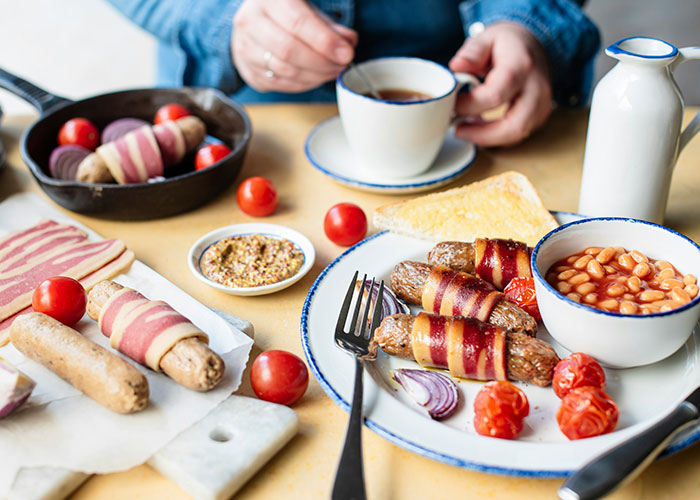 Breakfast plate with bacon-wrapped sausages, baked beans, grilled tomatoes, and coffee, illustrating powerful marketing campaigns.