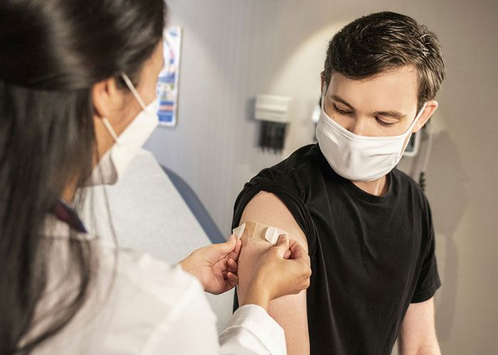 Healthcare worker applying a bandage on a masked patient’s arm, illustrating trust in powerful marketing campaigns.