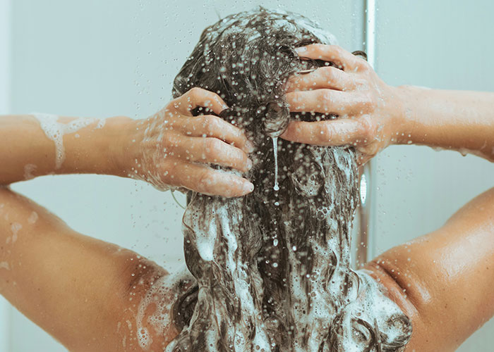 Person washing hair with shampoo in the shower, illustrating a powerful marketing campaign concept.