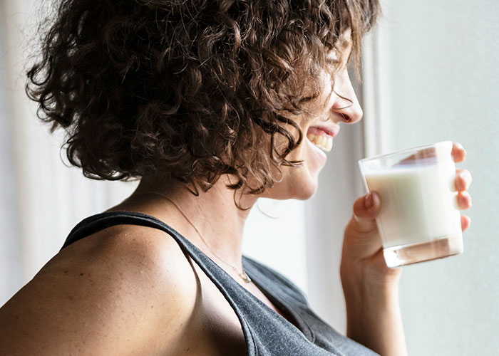 Woman with curly hair smiling and holding a glass of milk, illustrating powerful marketing campaigns concept.