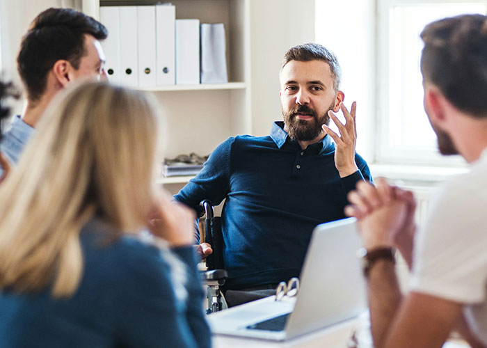 Man leading a team meeting in an office discussing powerful marketing campaigns and strategy ideas.