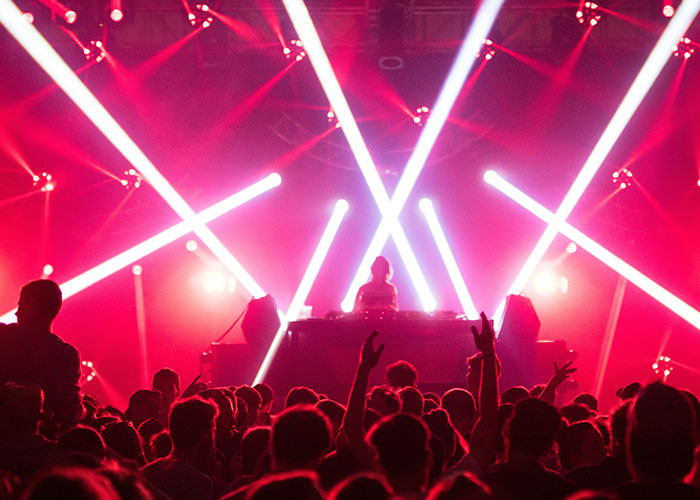 Crowd enjoying a live DJ performance with vibrant lighting, illustrating powerful marketing campaigns in action at events.