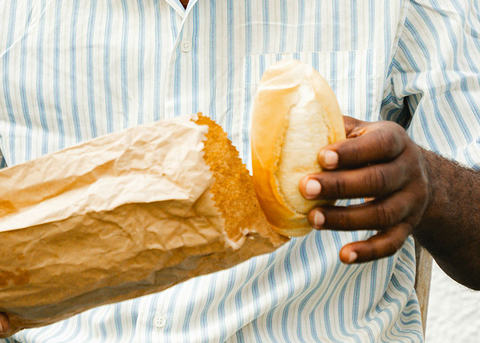 Man in striped shirt holding bread in paper bag, illustrating creative marketing campaigns with impactful storytelling.