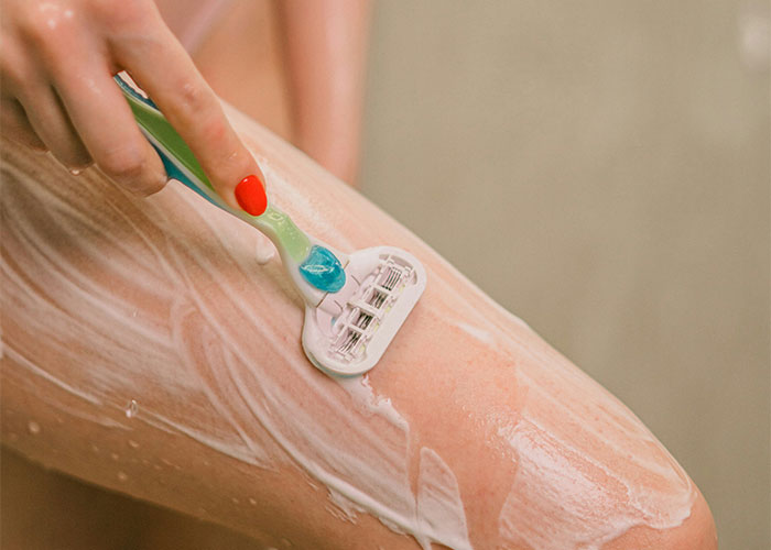 Person shaving leg with a razor, illustrating a marketing campaign using powerful imagery and persuasion techniques.