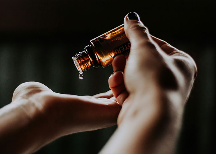 Hand pouring essential oil drop into open palm, illustrating impact of powerful marketing campaigns.