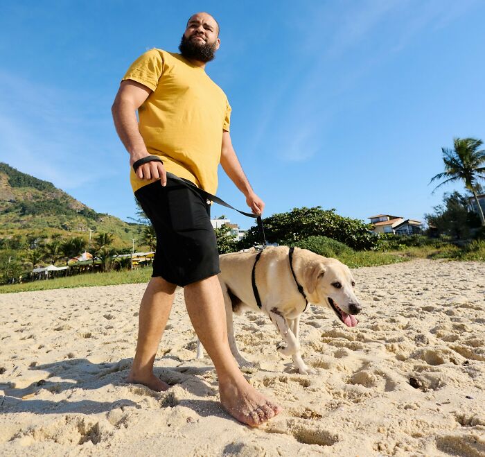 Man walking a dog on the beach on a sunny day, illustrating traits that make a man instantly unattractive to women.