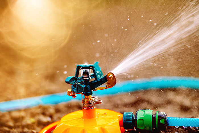 Garden sprinkler spraying water on soil near driveway with blocked neighbor truck causing petty revenge. - 5