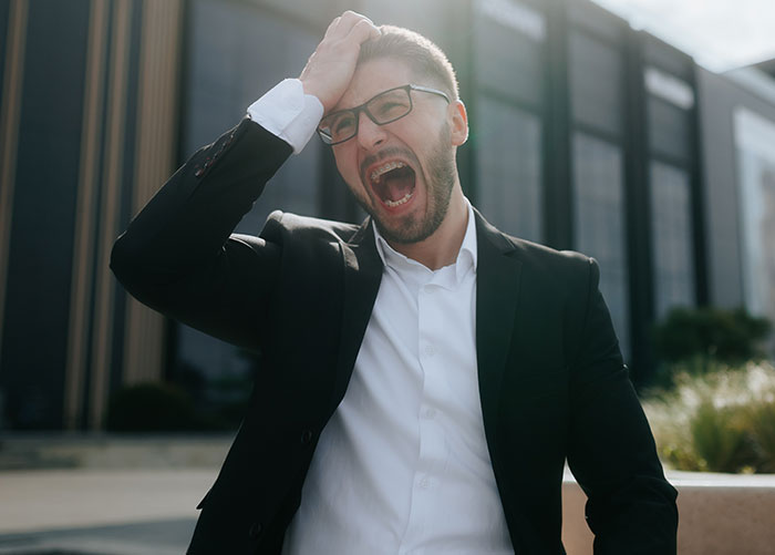 Man in business suit frustrated outside modern building, illustrating property shepherd conflict over car parking.