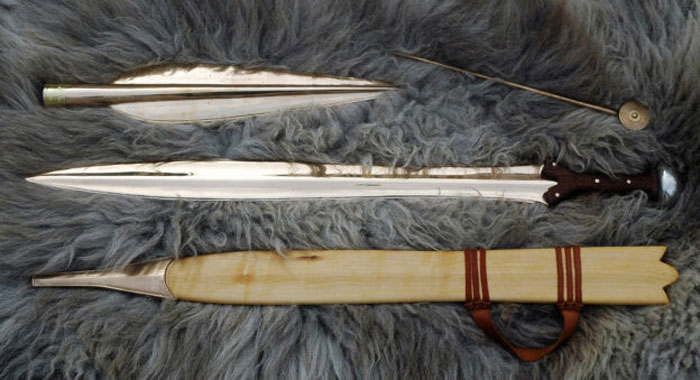 Neolithic spear and wooden sheath displayed on fur, related to groundbreaking discovery under Scottish school.