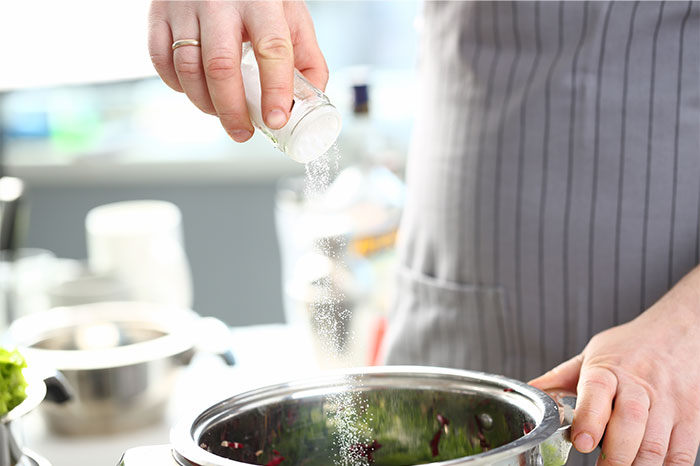 Person sprinkling salt into a pot in a kitchen while sharing cooking secrets and ingredients tips. - 20