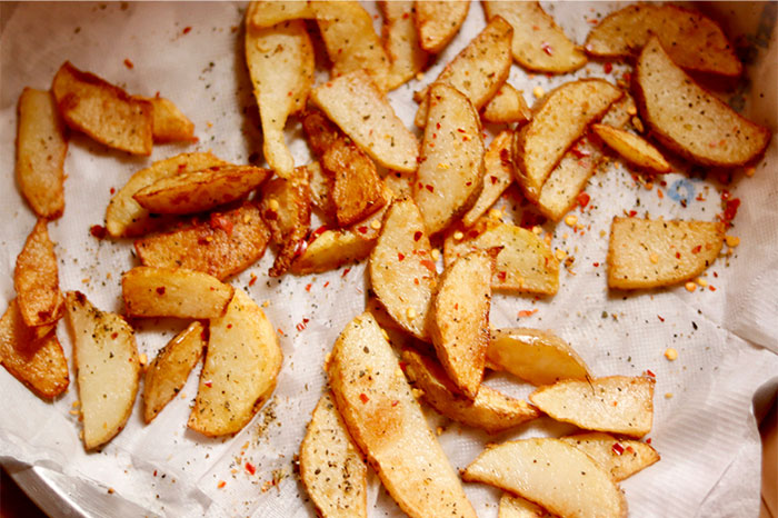 Seasoned potato wedges on parchment paper showcasing cooking secrets and unique ingredients for crispy results. - 29