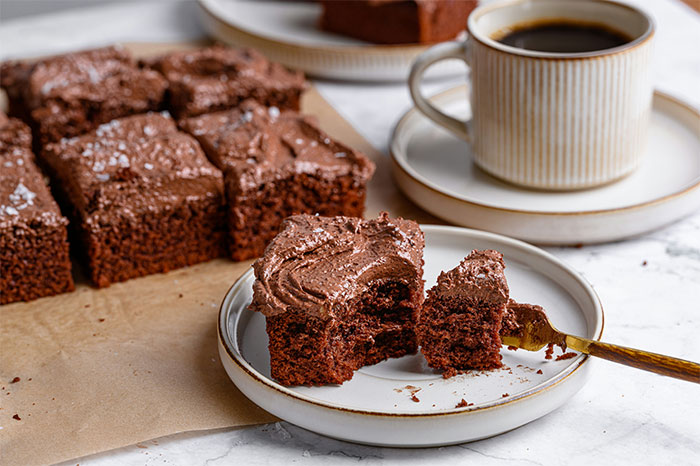 Chocolate frosted brownies on a plate with coffee, showcasing popular cooking secrets and ingredients for rich flavor. - 38