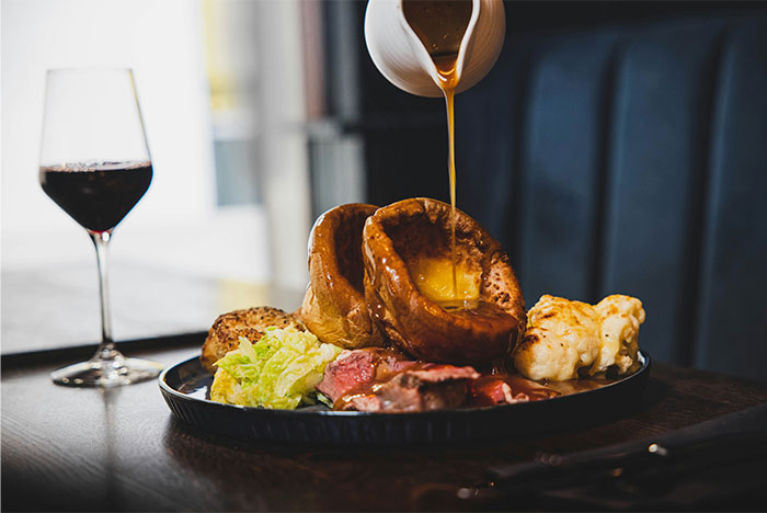A gourmet meal with gravy being poured over Yorkshire pudding, showcasing cooking secrets and unique ingredients. - 17