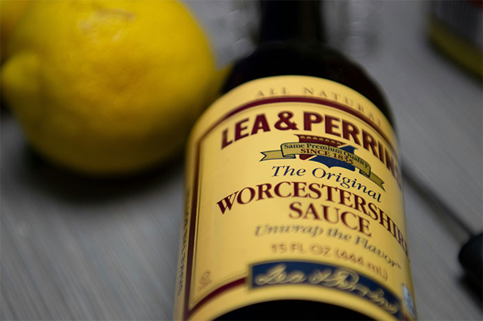 Lea & Perrins Worcestershire sauce bottle next to a lemon, highlighting cooking secrets and unique ingredients. - 10