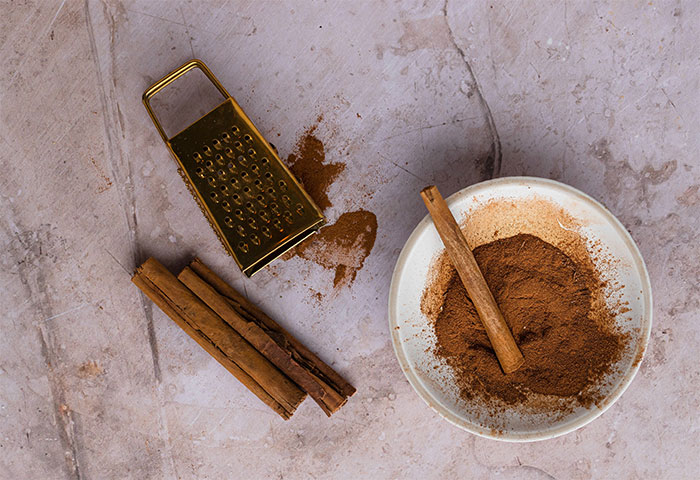 Cinnamon sticks and ground cinnamon on a plate with a grater, showcasing hidden cooking secrets and ingredients. - 5