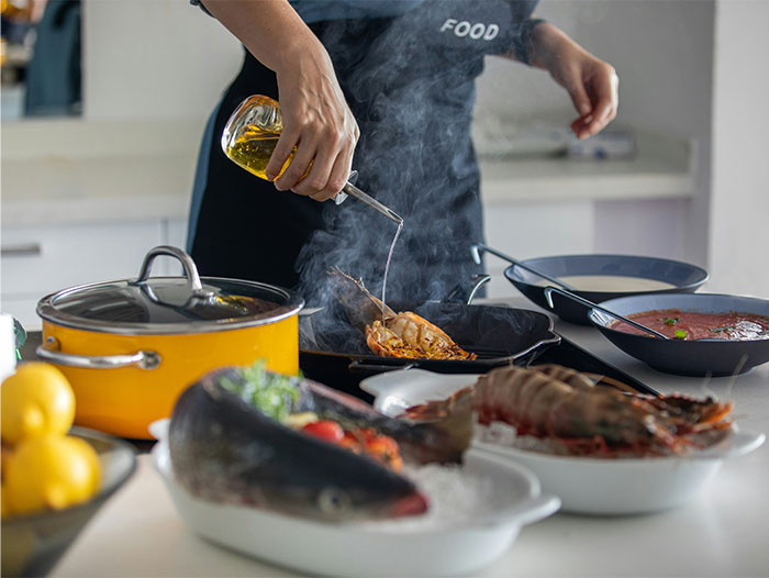 Person pouring oil while cooking seafood, illustrating cooking secrets and ingredients shared by home chefs. - 45
