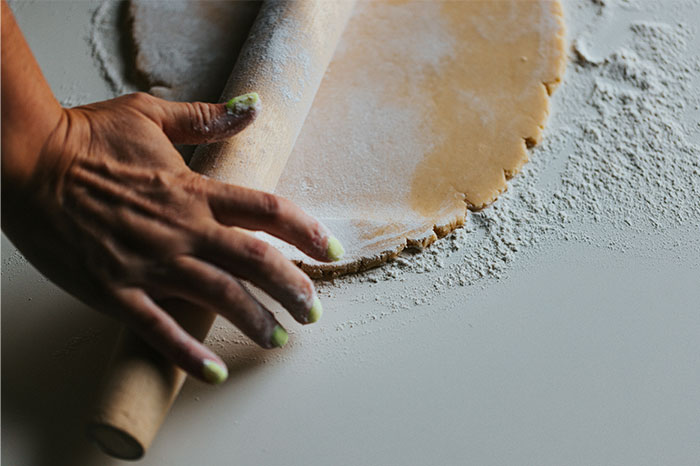 Hands rolling dough with a rolling pin on a floured surface sharing cooking secrets and ingredients. - 51