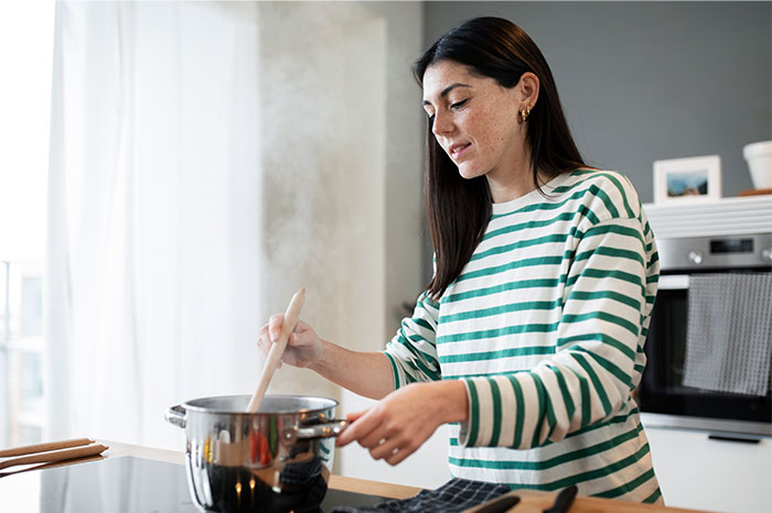 Woman cooking in a modern kitchen stirring a pot, sharing cooking secrets and ingredients for home recipes. - 37
