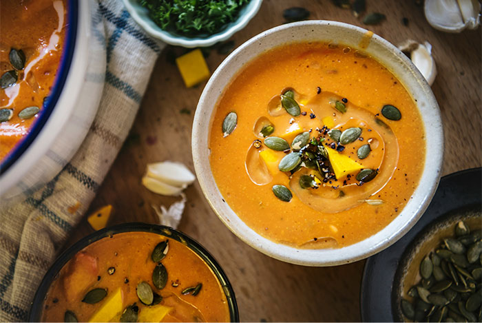 Creamy pumpkin soup garnished with seeds and herbs, showcasing cooking secrets and unique ingredients revealed by people. - 43