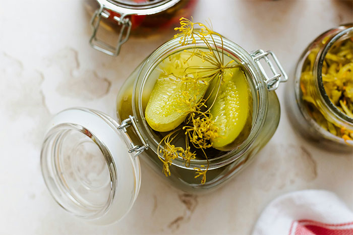 Glass jar with pickled cucumbers and dill, showcasing cooking secrets and unique ingredients in home recipes. - 32