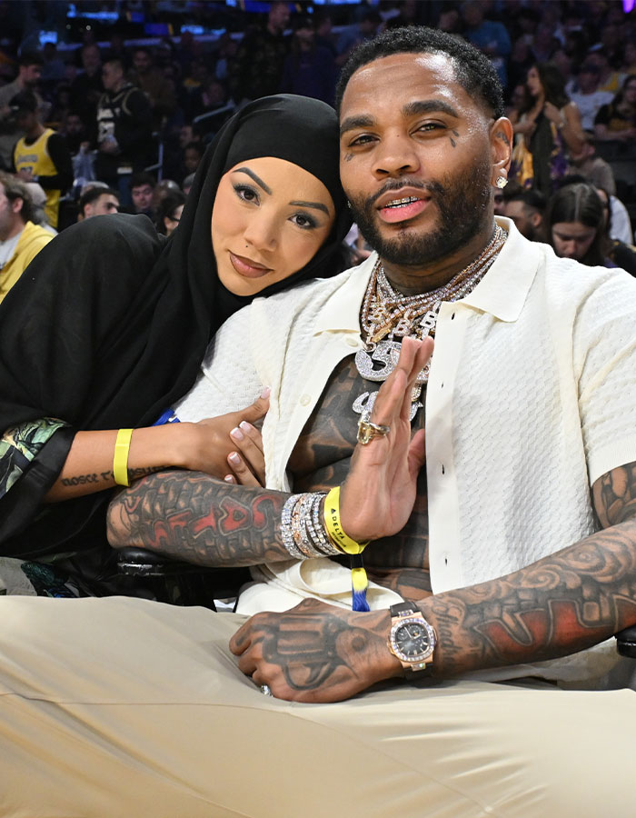 Influencer wearing hijab sitting next to a tattooed man with jewelry at a crowded indoor event. Influencer wearing hijab sitting next to a tattooed man with jewelry at a crowded indoor event.